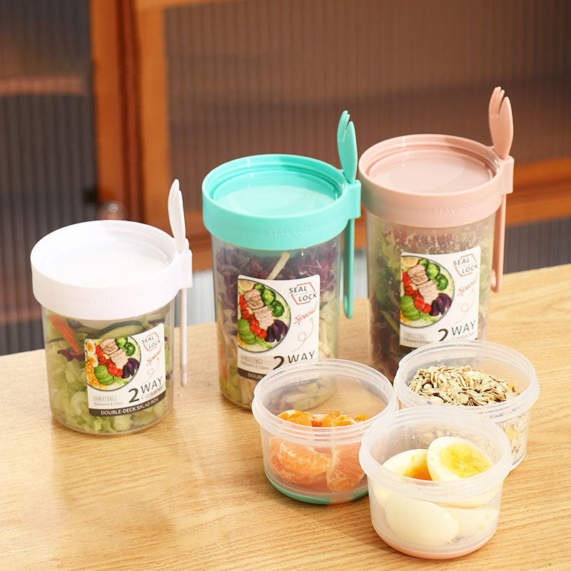 Dual-layer meal container with a spoon, featuring two compartments for organized food storage, ideal for lunches and meal prep.