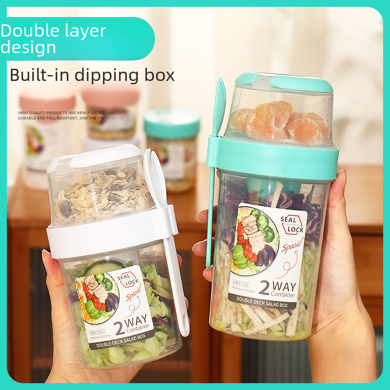 Dual-layer meal container with a spoon, featuring two compartments for organized food storage, ideal for lunches and meal prep.