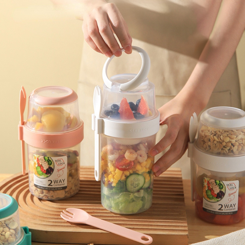 Dual-layer meal container with a spoon, featuring two compartments for organized food storage, ideal for lunches and meal prep.